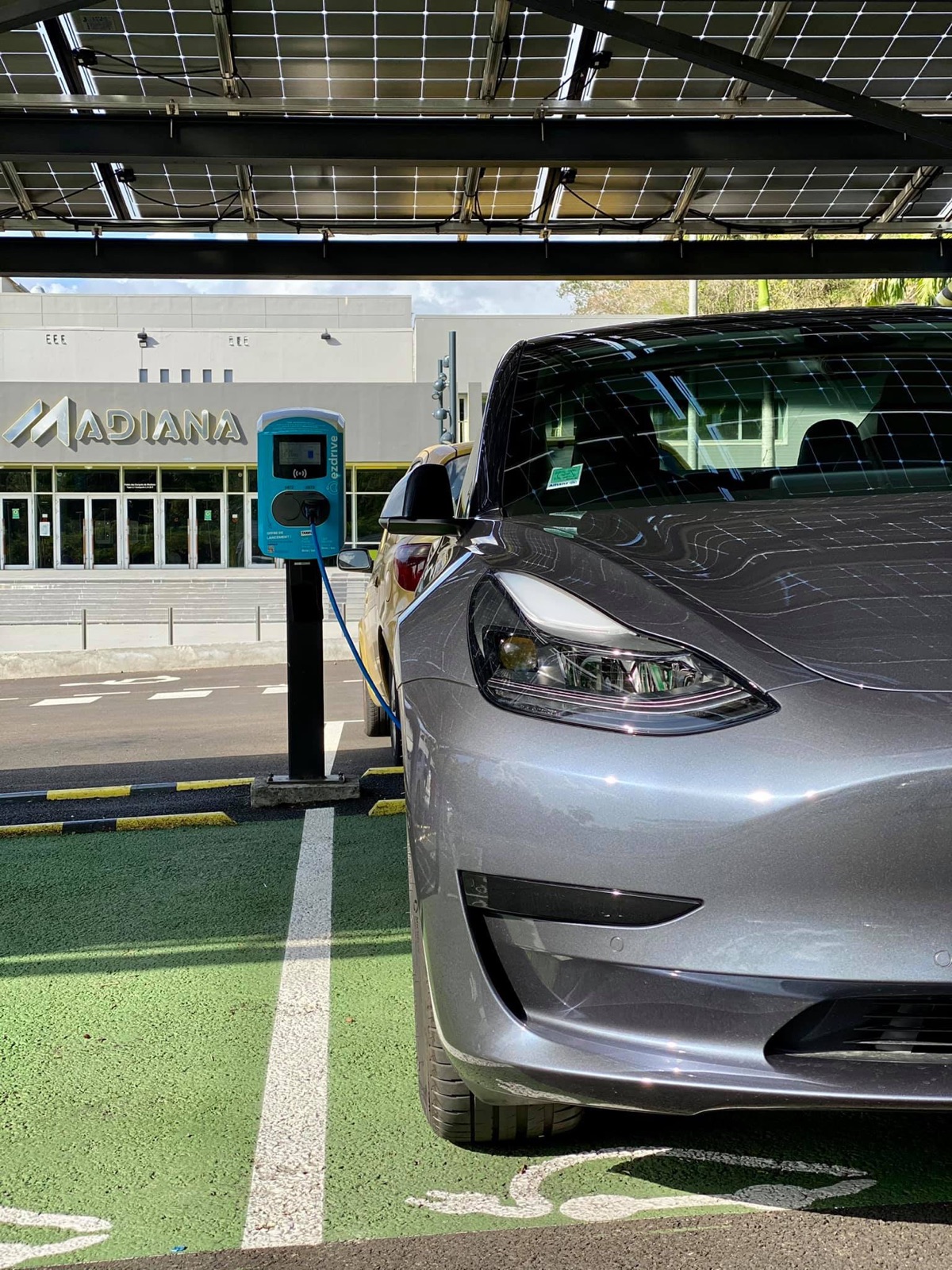 Tesla Model 3 en charge sur une borne publique EZdrive devant le centre commercial Madiana en Martinique